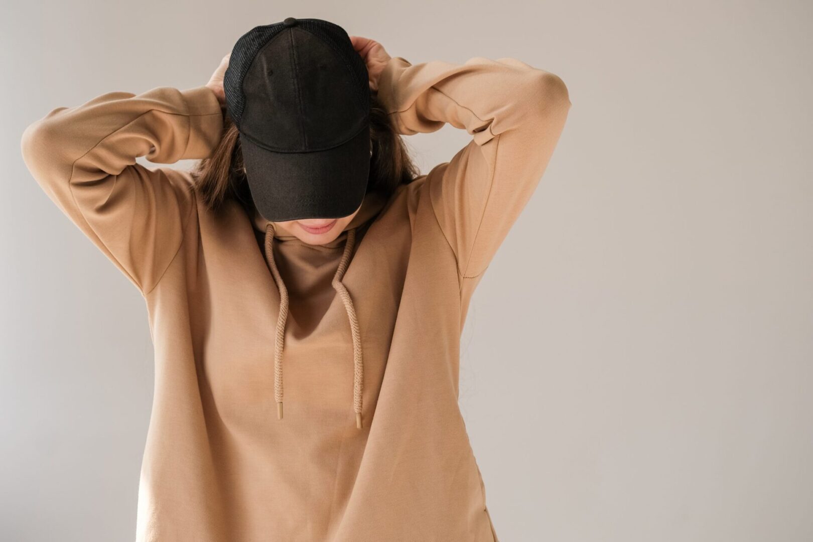 Person in hoodie and cap, facing down.